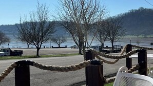 A waterfront restaurant with outdoor seating, a view of the lake, and a rope barrier. - Riverside Retreat 2 ~ One Story ~ 3bd/2ba ~ Steps to the River & Main St (Madison)