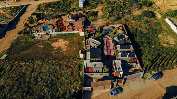 An aerial view of a residential area with multiple houses, a swimming pool, and a fenced parking area.