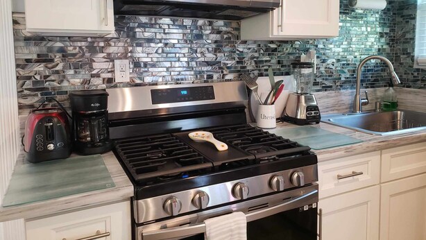 Una cocina moderna con estufa de acero inoxidable, microondas y cafetera.