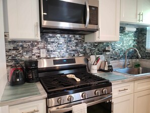 Una cocina moderna con estufa de acero inoxidable, microondas y cafetera.
