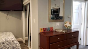Un dormitorio con cama, cómoda, espejo y televisor.