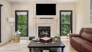 Una sala de estar con chimenea, televisor de pantalla plana y sofá de cuero marrón.