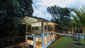A modern house with a glass enclosure, a covered porch, and a small bridge leading to a deck. - Casa Paraíso, Valle de Bravo. (Valle de Bravo)