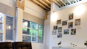 A room with a wooden ceiling, a black leather sofa, a wooden bench, a white desk with drawers, and a wall adorned with framed photographs. - Casa Paraíso, Valle de Bravo. (Valle de Bravo)