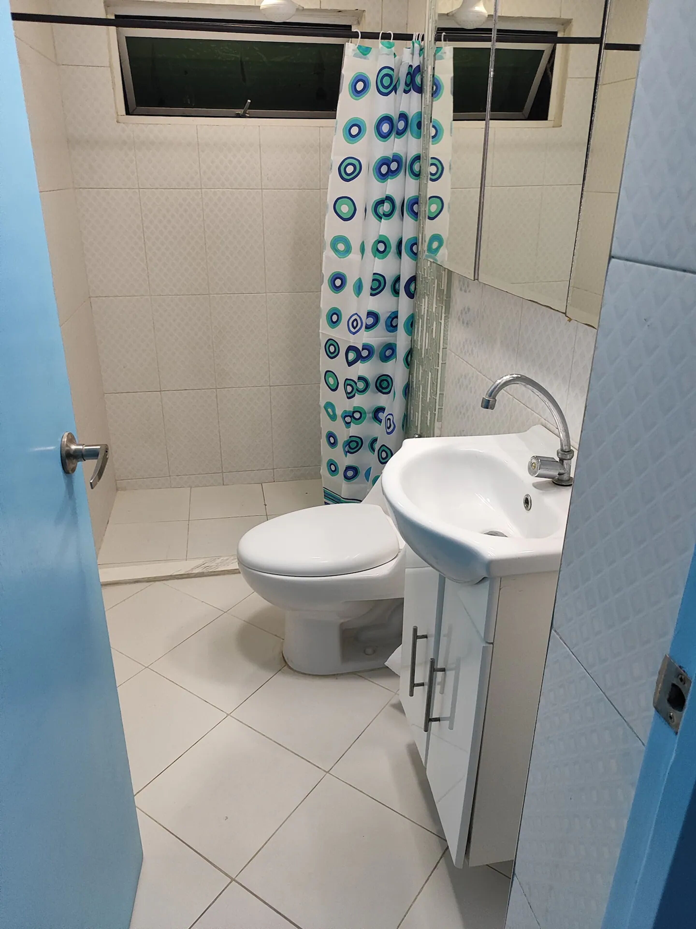 Een badkamer met toilet, wastafel en douchegordijn.