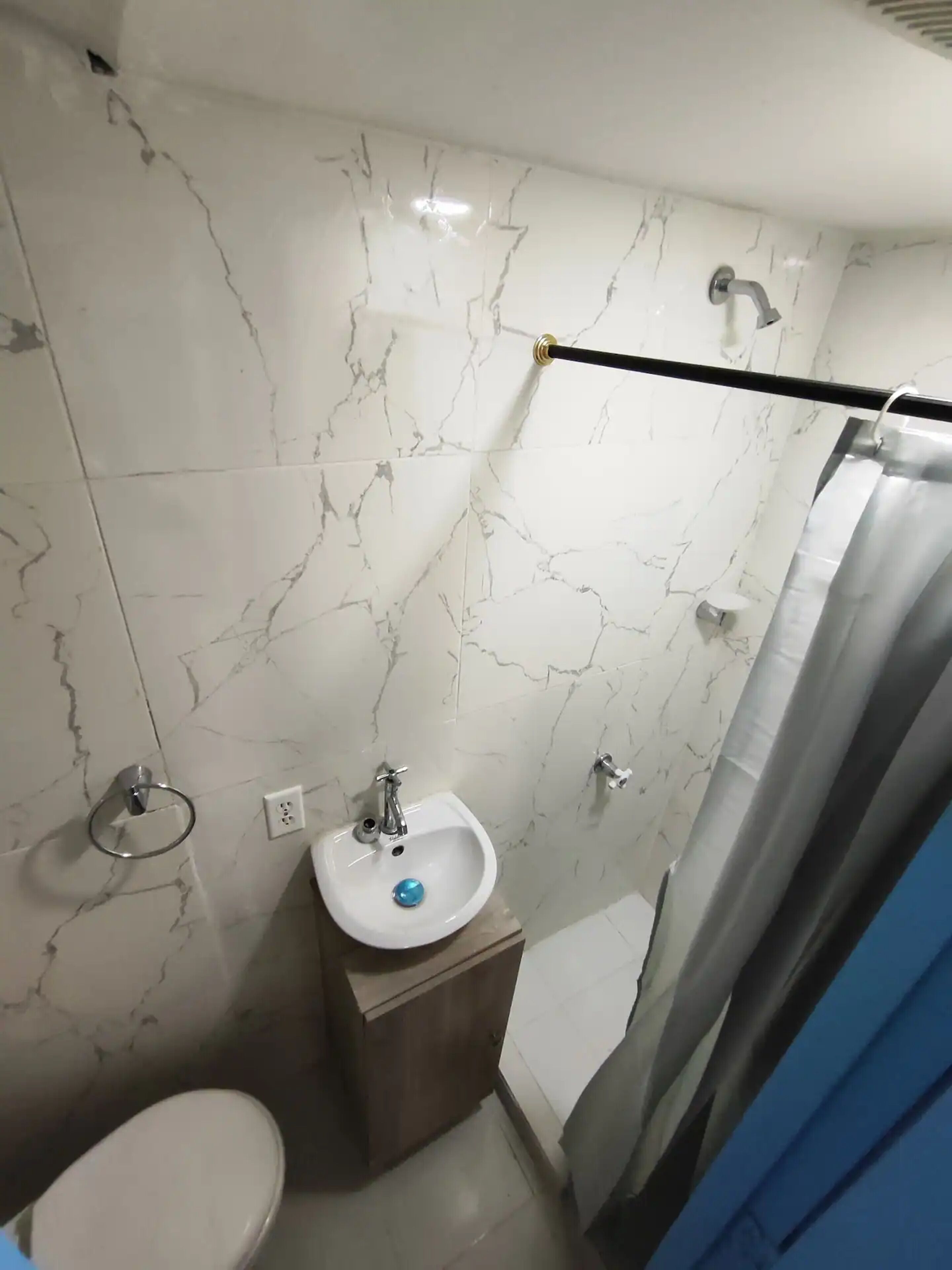 A bathroom with a white marble sink, a toilet, and a shower curtain.