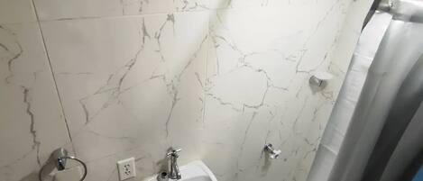 A bathroom with a white marble sink, a toilet, and a shower curtain.