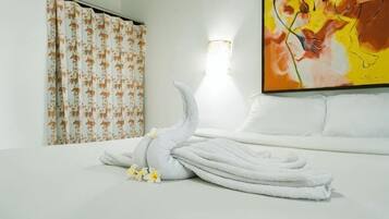 A hotel room with a neatly made bed, a wall-mounted artwork, and a shower curtain with a leaf pattern.