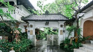 Une cour traditionnelle avec un toit en tuiles, une porte en bois et une végétation luxuriante.