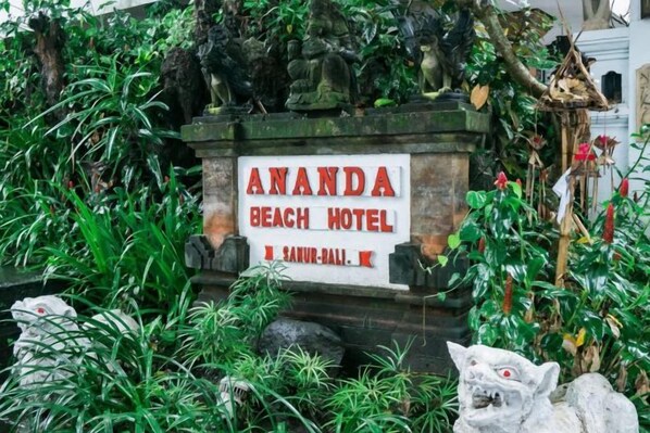 A sign for 'ANANDA BEACH HOTEL' with a stone base and surrounding greenery. - Urbanview Hotel Ananda Beach Sanur (Bali)
