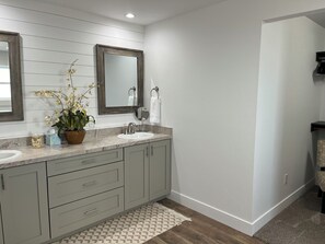 A bathroom with two sinks, a large mirror, a potted orchid, and a patterned rug. - Entire home in Valier, Montana (Valier)