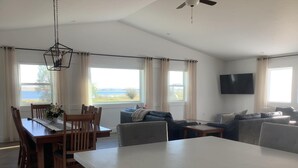 Un amplio salón con una mesa de comedor, sillas, un sofá y un televisor montado en la pared.