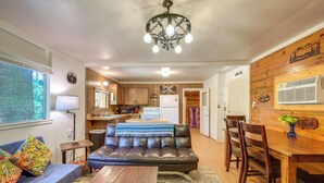 A cozy living room with a leather sofa, wooden dining table, and a chandelier. - Rustic Cabin w/ Patio: 8 Mi to Kings Canyon Park (Miramonte)
