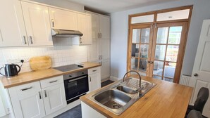 A modern kitchen with white cabinets, a wooden countertop, a built-in oven, and a double sink. - 4 bedroom accommodation in Gwithian (Gwithian)