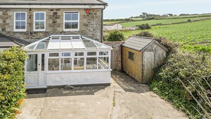 A stone house with a conservatory, a small wooden shed, and a garden. - 4 bedroom accommodation in Gwithian (Gwithian)