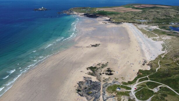An aerial view of a coastal area with a sandy beach, a lighthouse, and a small island. - 4 bedroom accommodation in Gwithian (Gwithian)