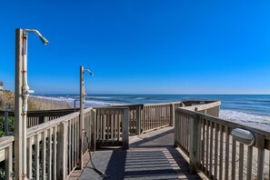 A wooden boardwalk leading to the beach with a clear view of the ocean.