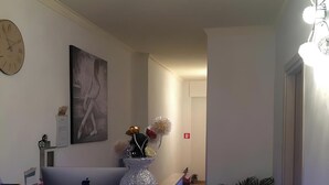 Una zona de recepción moderna con un mostrador, un reloj, una obra de arte enmarco y una planta en maceta.
