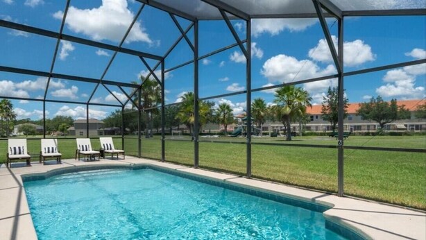 Une piscine à l’eau d’un bleu limpide, entourée d’un espace abrité avec des chaises, le tout sous une structure de toit en métal.