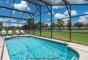 A swimming pool with a clear blue water, surrounded by a covered area with chairs, under a metal roof structure. - 4-bedroom Family Villa, gated Cumbrian Lakes community near Orlando theme Parks (Kissimmee)