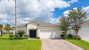 Une maison de plain-pied avec un garage, entourée de pelouses bien entretenues et d’un palmier.