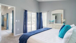 Une chambre à coucher avec un grand lit, une commode, un miroir et un ventilateur de plafond.