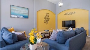 Un salon avec un canapé, une table basse et un téléviseur.