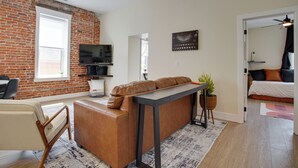 Een moderne woonkamer met een bakstenen muur, een bank, een televisie en een plafondventilator.