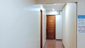 Un pasillo estrecho con una puerta de madera al final, un letrero en la pared y una lámpara sobre la puerta.
