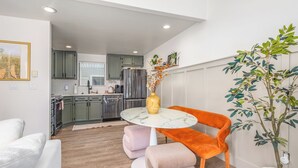 Une cuisine moderne avec des meubles gris, un réfrigérateur en acier inoxydable et une table en marbre agrémentée d’un vase.