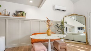 Une pièce moderne avec une table ronde, des sièges confortables, un grand miroir et une plante en pot.