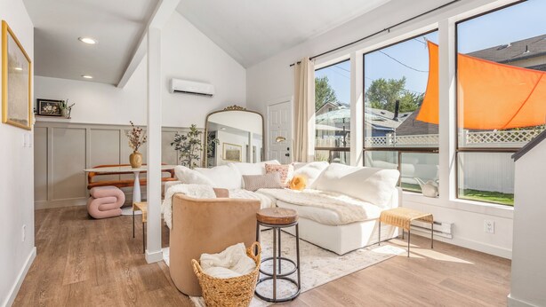 Un salon spacieux avec un canapé blanc, un tabouret rond en bois et un panier tressé.