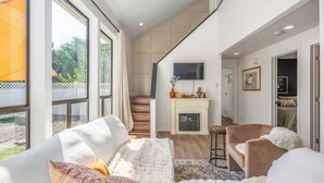 Un salon moderne doté d’une cheminée, de sièges confortables et de grandes fenêtres.