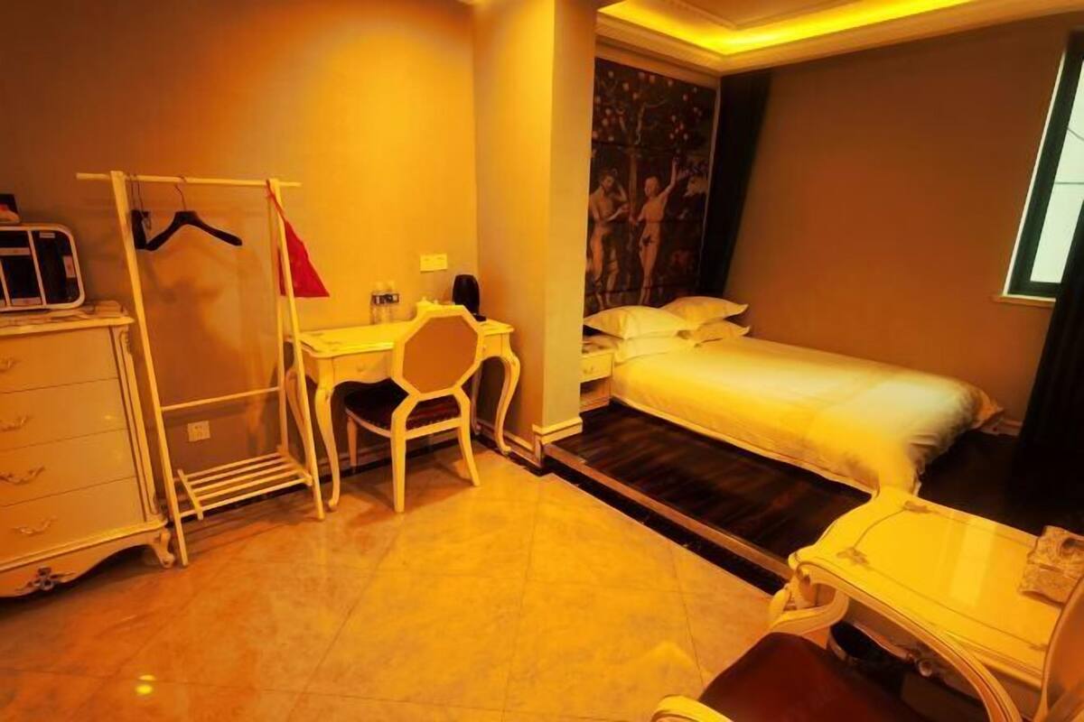 Una camera d'albergo con un letto, una scrivania, una sedia, un armadio e una finestra.