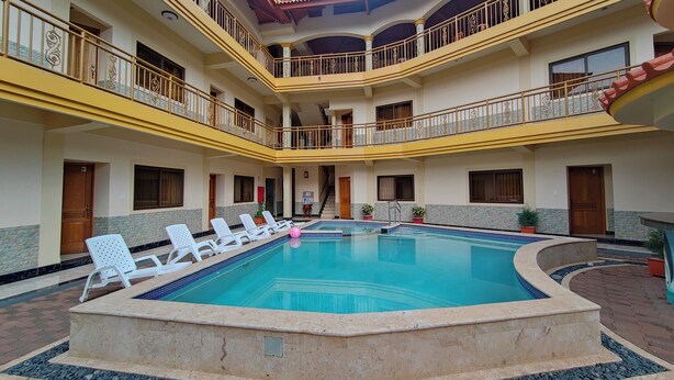A multi-level hotel with a central swimming pool, balconies with ornate railings, and a tiled floor around the pool. - Hotel Pacific Pearl (Punta Mala)