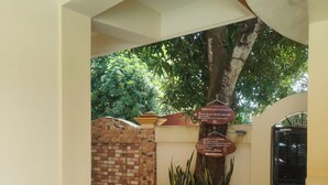 A clean, well-maintained indoor area with tiled flooring, potted plants, and a brick wall. - Hotel Pacific Pearl (Punta Mala)