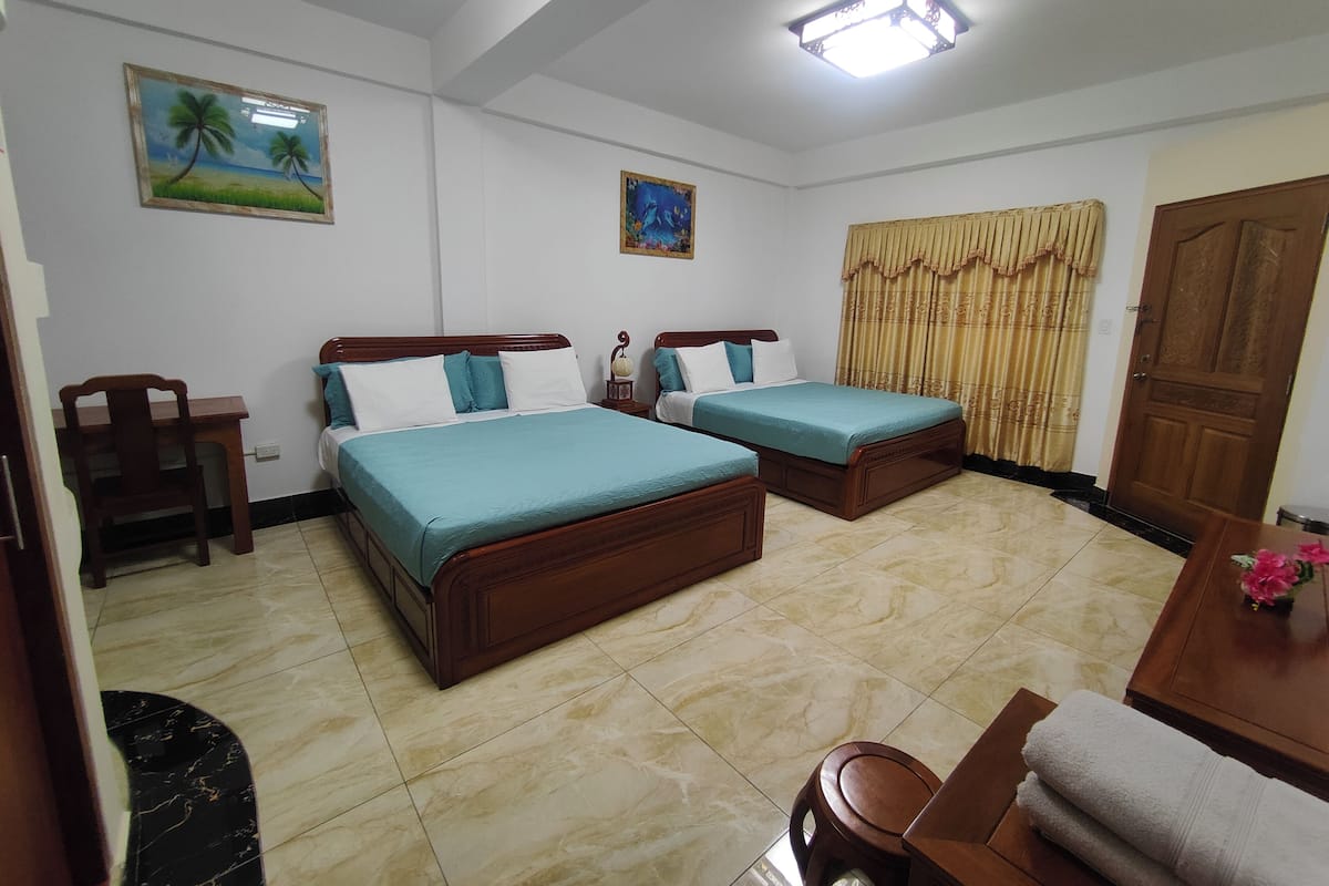 A bedroom with two wooden beds, a wooden chair, a small table, and a door.