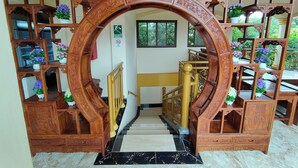 A wooden staircase with intricate carvings, leading to a landing with a view of greenery outside. - Hotel Pacific Pearl (Punta Mala)