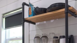 Una cocina con estantes de madera, un microondas y un ventanal.