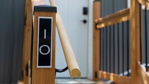 Una escalera de madera que lleva a una puerta con un cartel con número.
