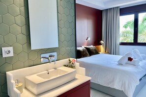 A modern hotel room with a large bed, a white sink, and a mirror. - Luxury house with pool, jacuzzi, and views of the sea and golf course. (Santa Cruz de Tenerife)