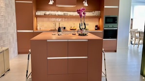 Una cucina moderna con isola centrale, illuminazione a sospensione e forno integrato.