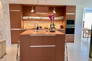A modern kitchen with a central island, pendant lighting, and a built-in oven. - Luxury house with pool, jacuzzi, and views of the sea and golf course. (Santa Cruz de Tenerife)