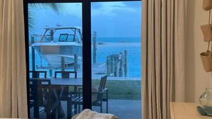 A bedroom with a large bed, a view of a boat on the water, and a patio area with outdoor furniture.