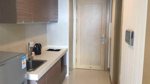 A compact kitchen with a built-in sink, a coffee maker, and a microwave. - Dalian Huafa New Town Hotel Apartment (Dalian)