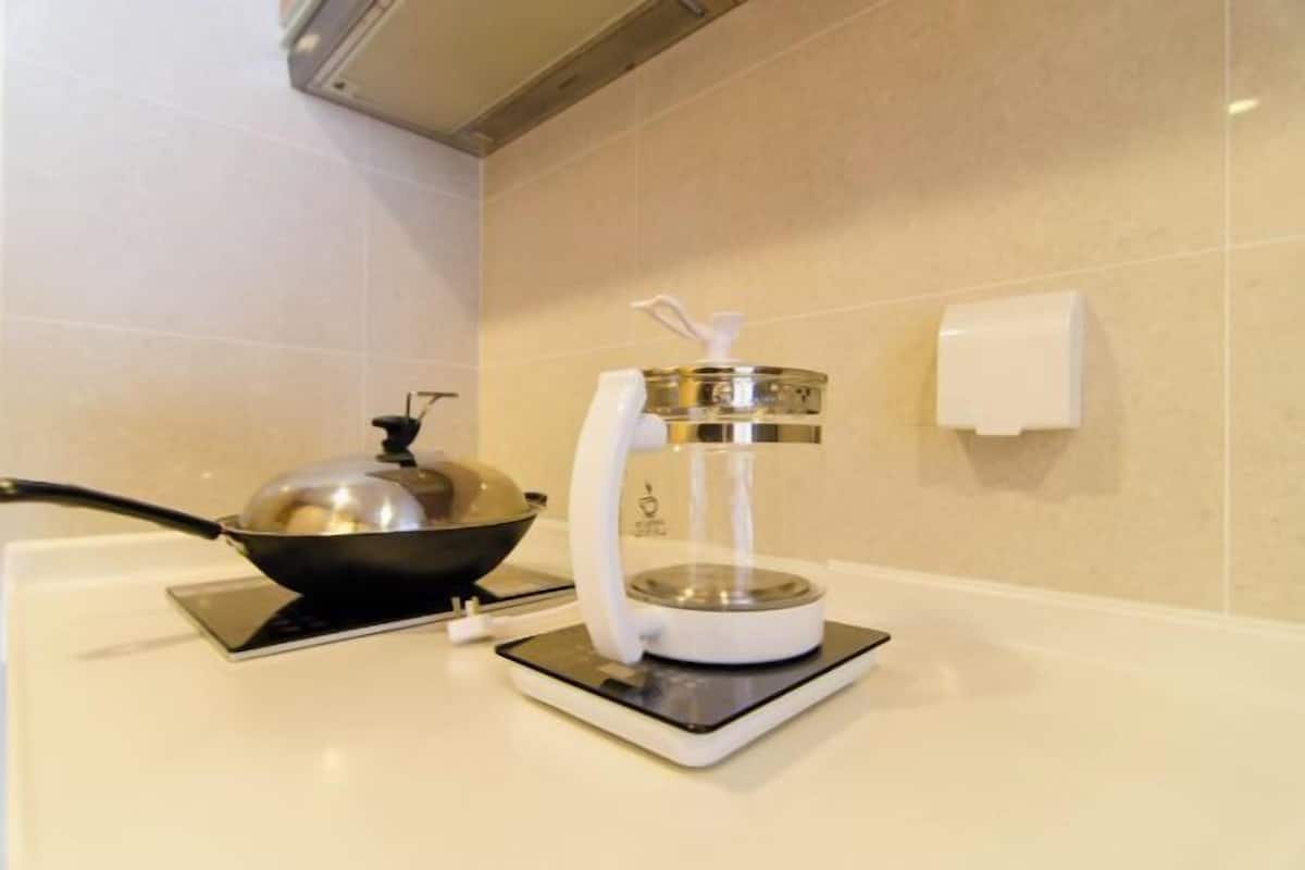 Una cocina con estufa, cafetera y tetera.