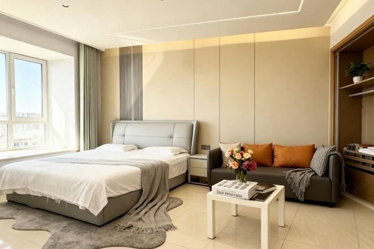 A modern bedroom with a bed, a nightstand, a sofa, and a coffee table.