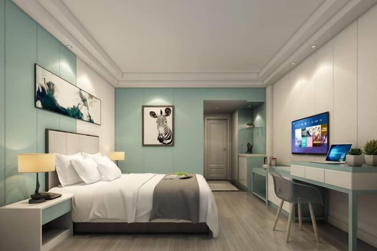 Une chambre d’hôtel moderne équipée d’un lit, de tables de chevet, d’un bureau et d’une télévision.
