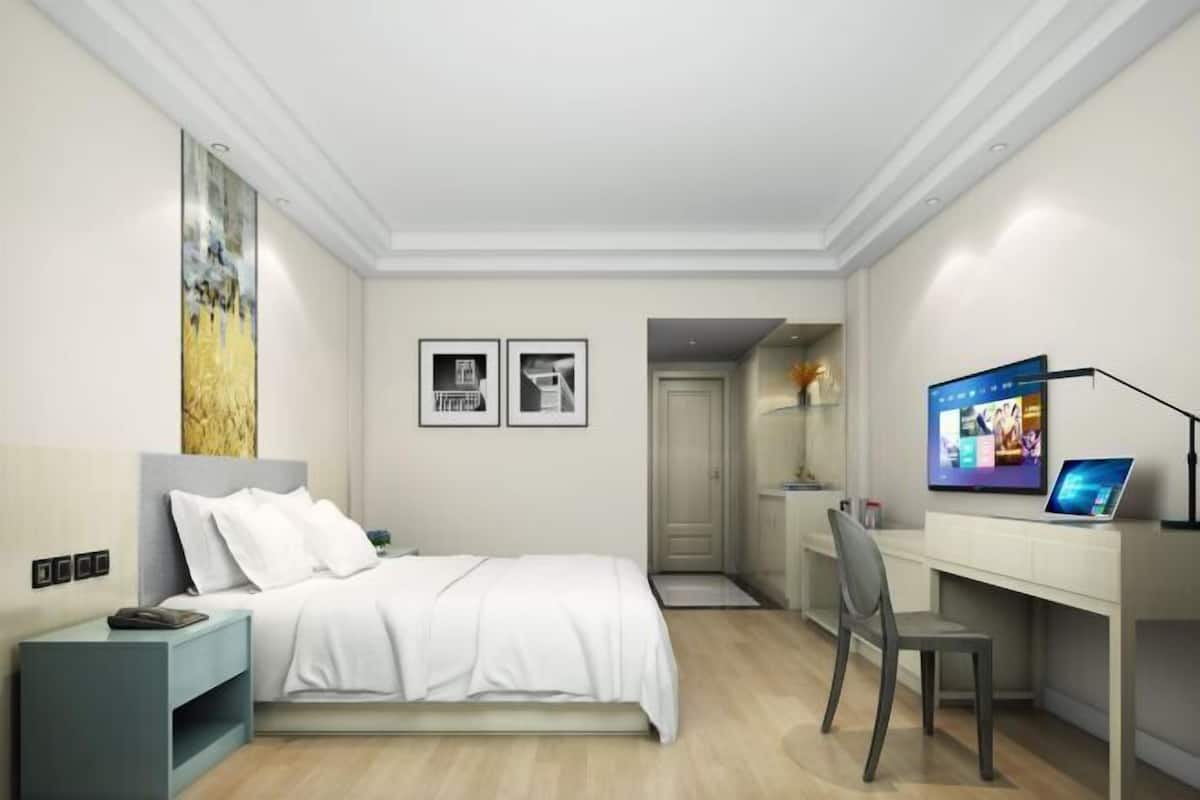 Une chambre à coucher moderne, avec un lit, un bureau et un téléviseur.