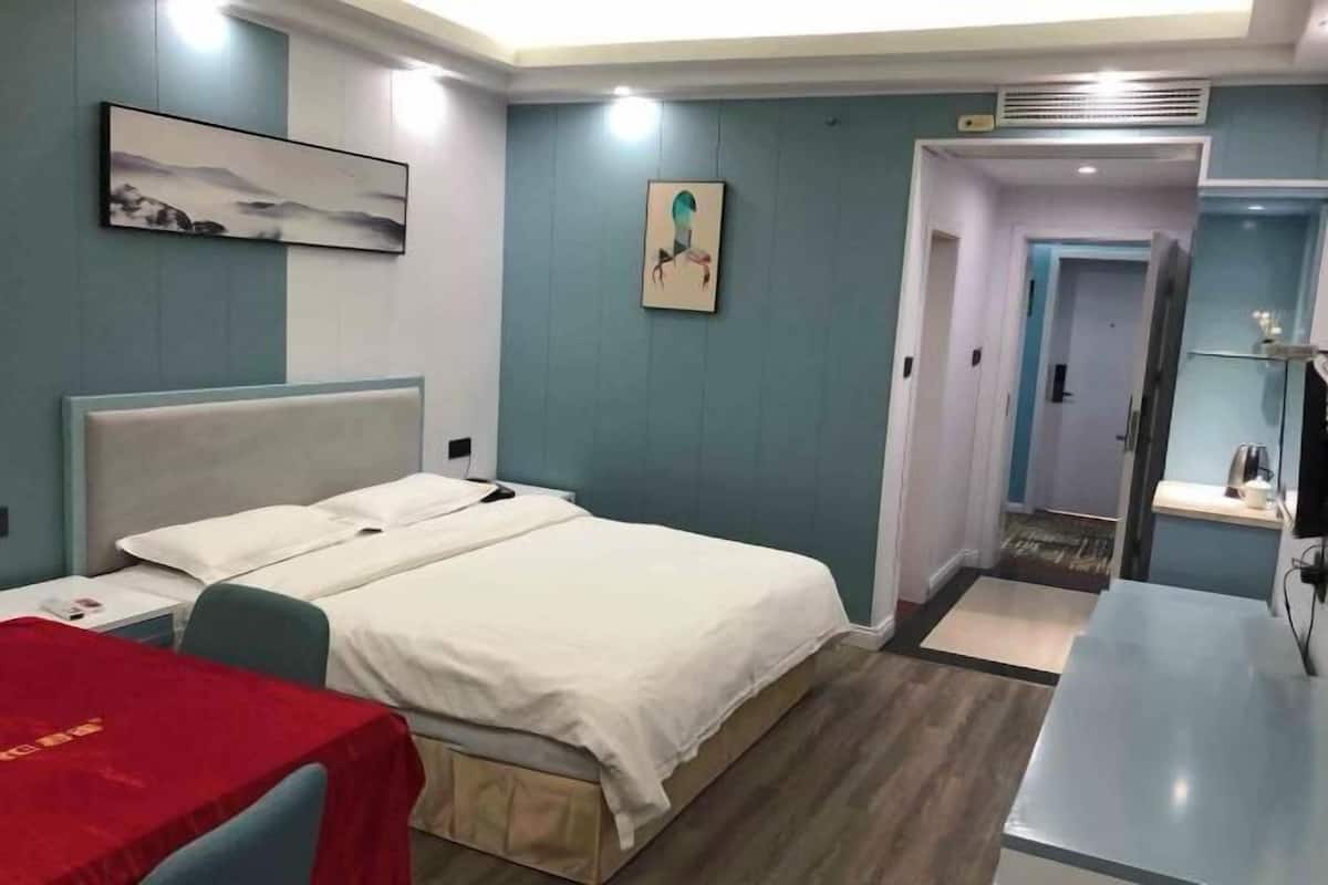 Une chambre d’hôtel avec un lit, un bureau, une chaise et un téléviseur.